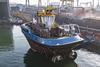 A fully electric tug alongside a dock