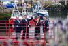 Four members of Eyemouth Harbour Trust standing on a red gangway holding aloft the harbour's masterplan