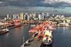 Manila South Harbour, Philippines, showing ships portside, a number of ship-to-shore cranes and high rise buildings in the background