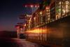 The image shows a ship berthed at a lit up dock at night