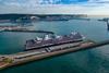 The pictures shows a Holland America Line cruise ship against a backdrop of the White Cliffs of Dover