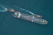 An aerial shot of a cargo ship at sea with two tugs