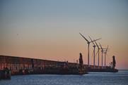 The image shows Bilbao Port by sunset with wind turbines in the background