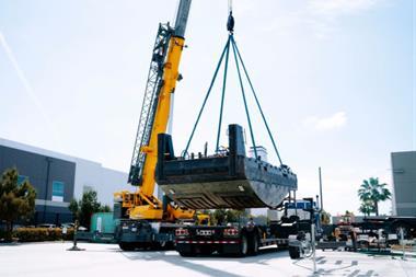 The image shows the 26 foot electric tug being lifted during construction