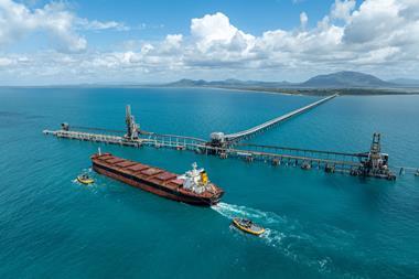 A ship with two tugs at the end of a very long pier at NQXT Port