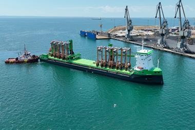 Eight hybrid straddle carriers arrive on a green barge at the Port of Thessaloniki