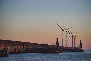 The image shows Bilbao Port by sunset with wind turbines in the background