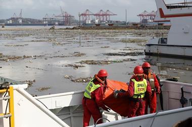 A team of workers in a port clearing waste from the water.