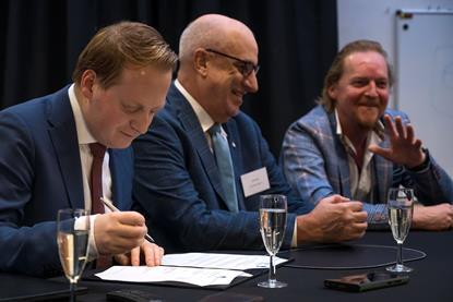 The image shows Photo: Mark Lengton, Joseph Krapf and Paul Vosbeek signing the agreement