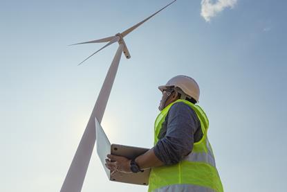 engineer using a laptop near wind turbine