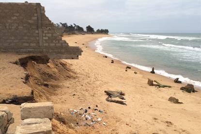 Collapsed buildings on the Togo coast, with a brick wall undercut by beach erosion.