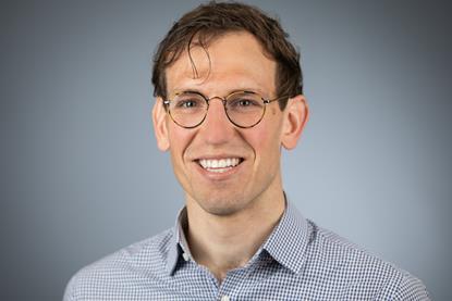 A picture of Cameron Gook, a white man wearing glasses and a blue shirt