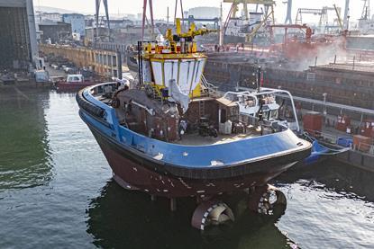 A fully electric tug alongside a dock