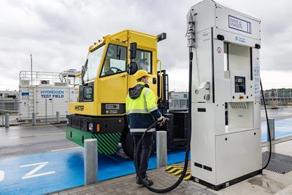 The image shows a Hyster hydrogen fuel cell-powered terminal tractor in action at HHLA