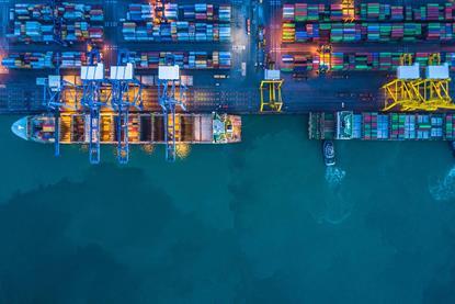 The image shows vessels berthed at a terminal with a container yard in the background