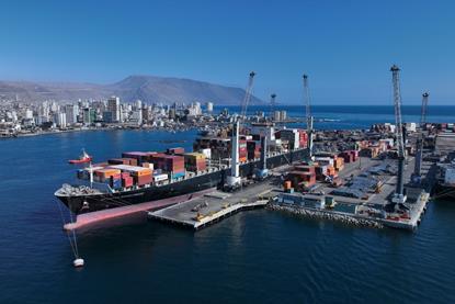 Iquique Terminal Internacional in Chile. Image shows a container ship at port with the city and low mountains behind