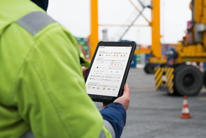 yourKONECRANES displayed on a tablet being held by a man in a high-vis jacket