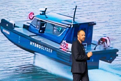 Yinson GreenTech employee standing in front of an image of the Hydroglyder fully electric hydrofoil