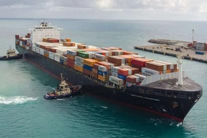 The image shows Svitzer tugs guiding a container ship into port