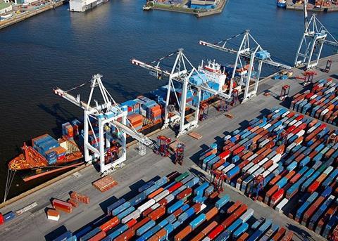 Aerial shot of a container ship at dock at the Port of Hamburg with four ship-to-shore cranes and containers dockside
