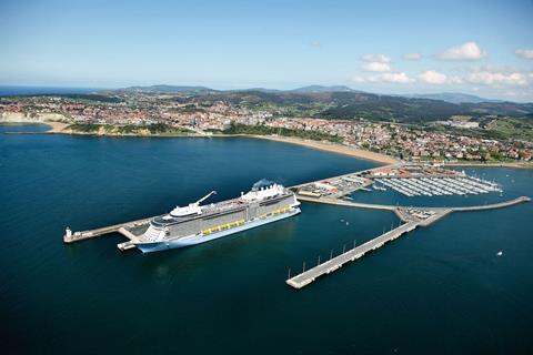 A cruise ship docks at the Port of Bilbao, Spain with mountains in the background